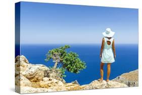 Back view of woman with fashion dress and hat looking at the sea from cliffs, Crete-Roberto Moiola-Stretched Canvas