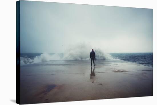 Back View Portrait of Young Man Standing against the Sea on a Large Concrete Pier with Big Wave Bea-GaudiLab-Stretched Canvas