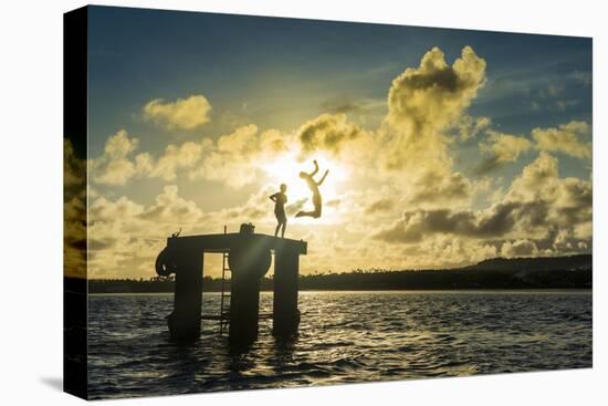 Backlit local boys jumping into the water of the lagoon of Wallis from a platform, Wallis and Futun-Michael Runkel-Stretched Canvas