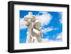 Beautiful Infant Angel Leaning on a Christian Cross with a Blue Sky Background (With Space for Text-Kamira-Framed Photographic Print