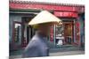 Beijing, China. Old Man with Conical Hat Passing in Front of a Shop in a Hutong of Beijing-Matteo Colombo-Mounted Photographic Print