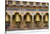 Bhutan. Spinning prayer wheels along a temple wall.-Brenda Tharp-Stretched Canvas