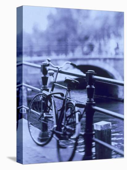 Bicycle on Rail by Canal, Amsterdam, Netherlands-Walter Bibikow-Stretched Canvas