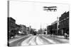 Biplane over a Small Town-J.H. Cave-Stretched Canvas