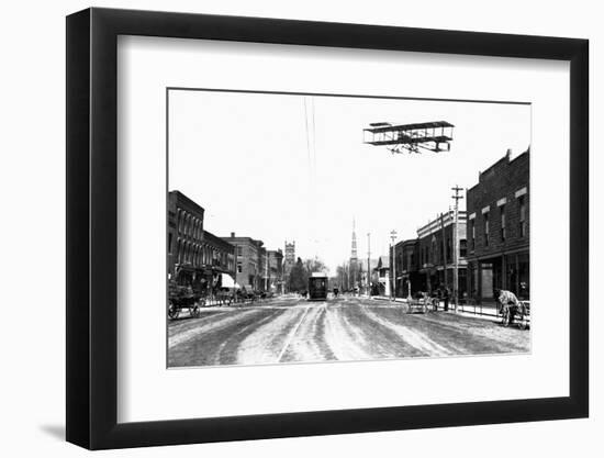 Biplane over a Small Town-J.H. Cave-Framed Photographic Print