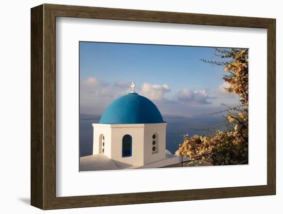 Blue domed Greek Orthodox church with bougainvillea flowers in Oia, Santorini, Greece.-Michele Niles-Framed Photographic Print