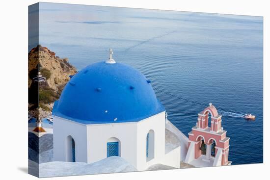 Blue domed white church overlooking boat in Aegean Sea, Santorini, Cyclades-Ed Hasler-Stretched Canvas