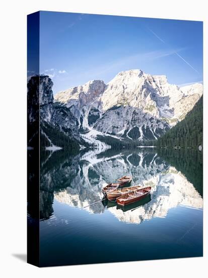 Boats moored in Lake Braies (Pragser Wildsee) with mountains reflected in water-Roberto Moiola-Stretched Canvas