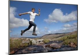 Boy (Aged 17) Jumping across Upland Stream-Mark Hamblin-Mounted Photographic Print