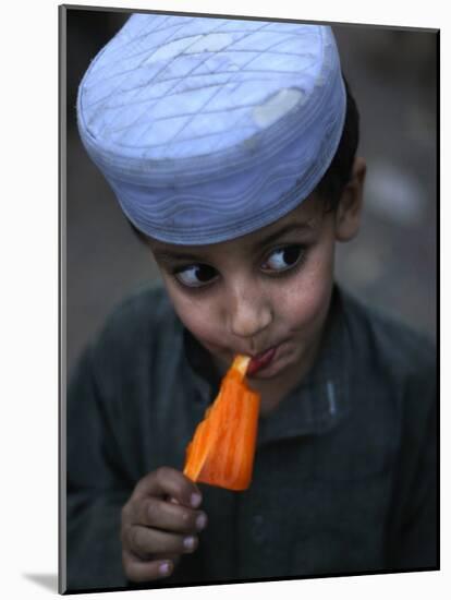 Boy Eats an Ice Lolly in a Neighborhood on the Outskirts of Islamabad, Pakistan-null-Mounted Photographic Print