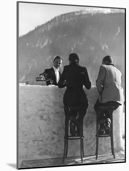 British Couple on High Stools at Ice Bar Outdoors at Grand Hotel as Waiter Pours Them Drinks-Alfred Eisenstaedt-Mounted Photographic Print