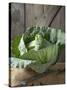 Cabbage on Chopping Board in Front of Wooden Wall-null-Stretched Canvas