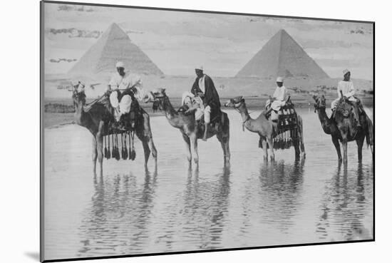 Camels with Native Riders on Board Stand in Reflective Floodwaters-null-Mounted Art Print