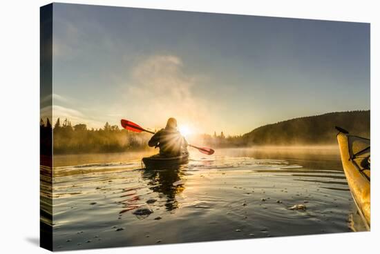 Canada, British Columbia. A kayaker paddles in morning mist on a Canadian lake.-Gary Luhm-Stretched Canvas