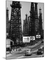 Car Traffic on Highway Next to Advertising Billboards and Oil Well Towers, Signal Hill Oil Field-Andreas Feininger-Mounted Photographic Print