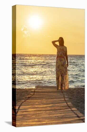 Charming woman contemplating the sea at sunset standing on Matala beach, Crete-Roberto Moiola-Stretched Canvas