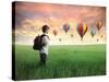 Child Carrying A Backpack Standing On A Green Meadow With Hot-Air Balloons In The Background-olly2-Stretched Canvas