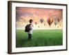 Child Carrying A Backpack Standing On A Green Meadow With Hot-Air Balloons In The Background-olly2-Framed Art Print