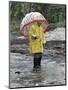 Child in Rain Gear with Umbrella Playing in Puddle.-Nora Hernandez-Mounted Giclee Print