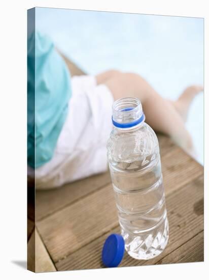 Child Sitting Beside Bottle of Water on Edge of Pool-null-Stretched Canvas