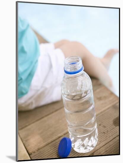 Child Sitting Beside Bottle of Water on Edge of Pool-null-Mounted Photographic Print