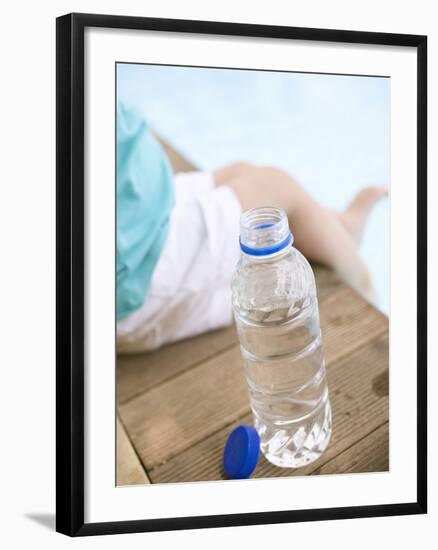 Child Sitting Beside Bottle of Water on Edge of Pool-null-Framed Photographic Print