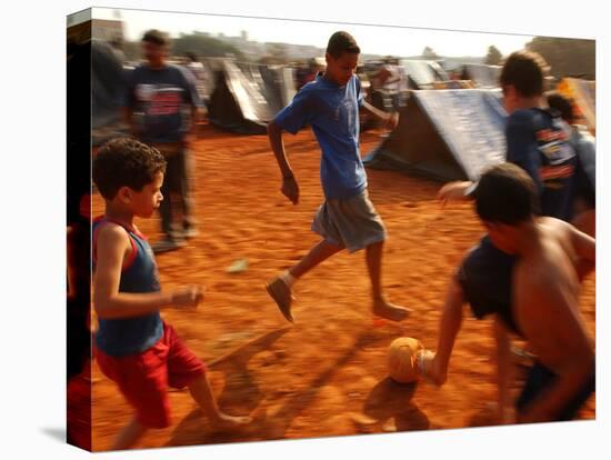 Children Play Soccer Between Tents Placed on a Dusty Lot-null-Stretched Canvas