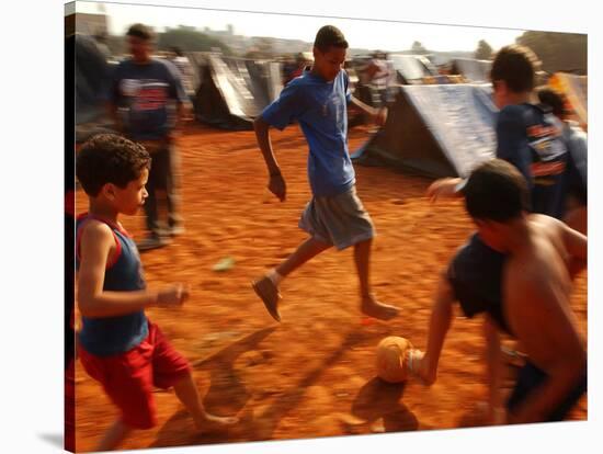Children Play Soccer Between Tents Placed on a Dusty Lot-null-Stretched Canvas
