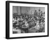 Children Sitting at their Desks in a Classroom, Teachers at the Rear of the Room-null-Framed Photographic Print