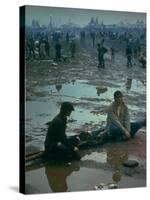 Chuck Morgan Sitting in the Mud and Water with a Friend, During Woodstock Music and Art Fair-John Dominis-Stretched Canvas