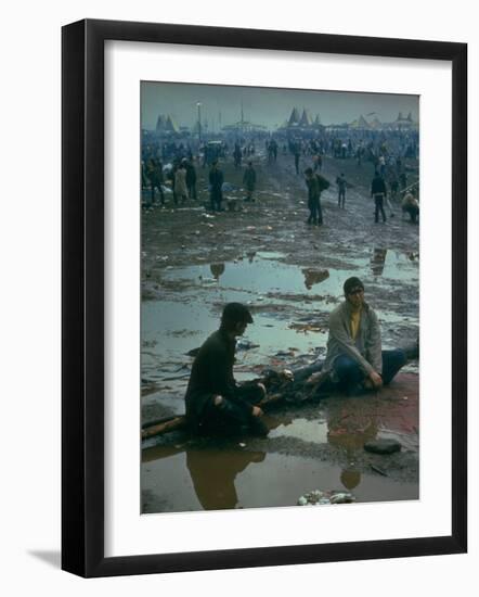 Chuck Morgan Sitting in the Mud and Water with a Friend, During Woodstock Music and Art Fair-John Dominis-Framed Photographic Print