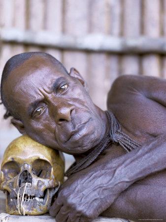 Portrait of an Asmat Tribesman Leaning on a Human Skull, Irian Jaya, Indonesia