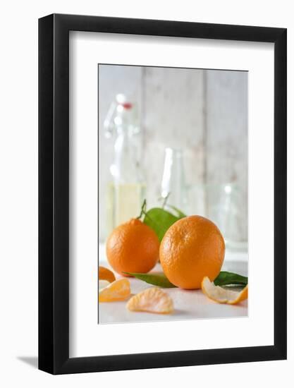 Clementines with Foliage, Pieces of Clementines and Peel in Front of Bright Background-Jana Ihle-Framed Photographic Print