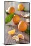 Clementines with Foliage, Pieces of Clementines and Peel on a Wooden Table-Jana Ihle-Mounted Photographic Print