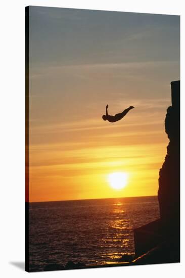 Cliff Diver above Setting Sun-Bob Krist-Stretched Canvas