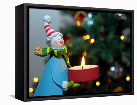 Close-Up of a Snow Man Candle in Front of a Tree with Christmas Lights-Winfred Evers-Framed Stretched Canvas