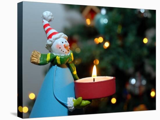 Close-Up of a Snow Man Candle in Front of a Tree with Christmas Lights-Winfred Evers-Stretched Canvas