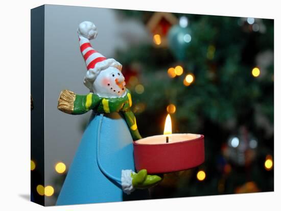 Close-Up of a Snow Man Candle in Front of a Tree with Christmas Lights-Winfred Evers-Stretched Canvas