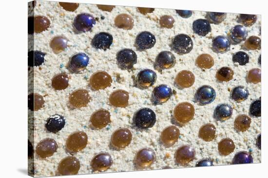 Close up of glass marbles in sand-John Gollings-Stretched Canvas