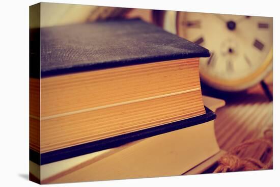 Closeup of a Pile of Old Books and an Old Alarm Clock on a Desk, with a Retro Effect-nito-Stretched Canvas