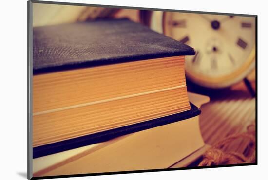Closeup of a Pile of Old Books and an Old Alarm Clock on a Desk, with a Retro Effect-nito-Mounted Photographic Print