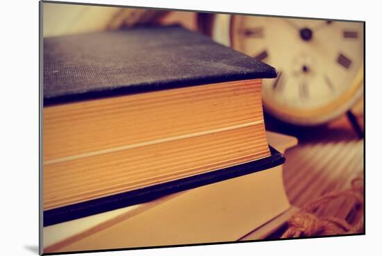 Closeup of a Pile of Old Books and an Old Alarm Clock on a Desk, with a Retro Effect-nito-Mounted Photographic Print