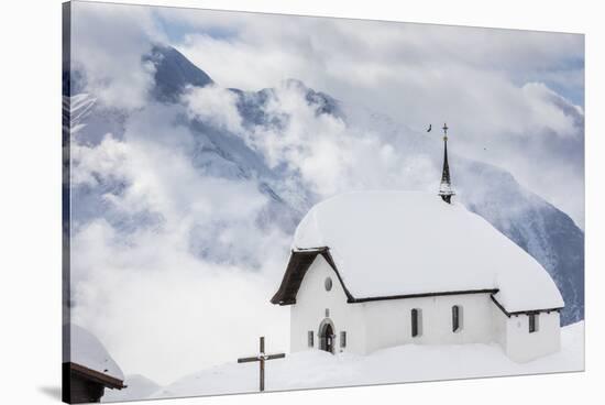 Clouds Above the Mountain Huts and Church Covered with Snow, Bettmeralp, District of Raron-Roberto Moiola-Stretched Canvas