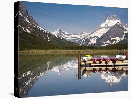 Colorful Canoes Line the Dock at Many Glacier Lodge on Swiftcurrent Lake During Sunrise-Brad Beck-Stretched Canvas