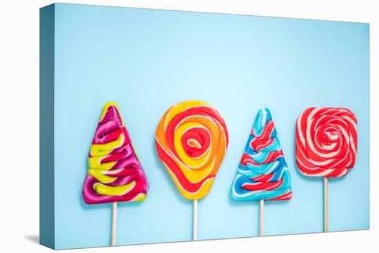 Colorful Vibrant Lollipops, Flat Lay on Blue Background-Marcin Jucha-Stretched Canvas