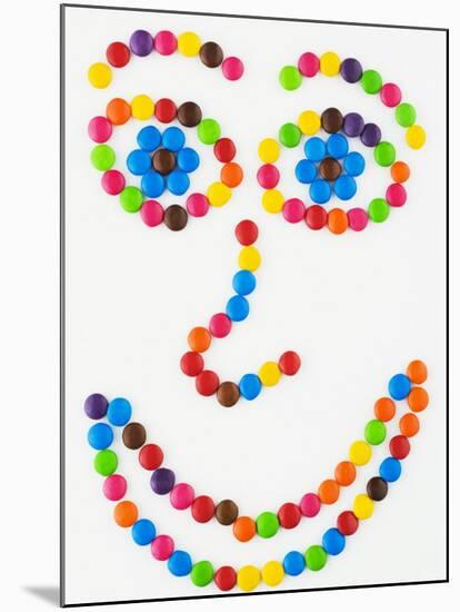 Coloured Chocolate Beans Forming a Smiling Face-Greg Elms-Mounted Photographic Print