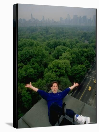 Comedian Jerry Seinfeld Perching Precariously on Roof Ledge Overlooking Central Park-Ted Thai-Stretched Canvas