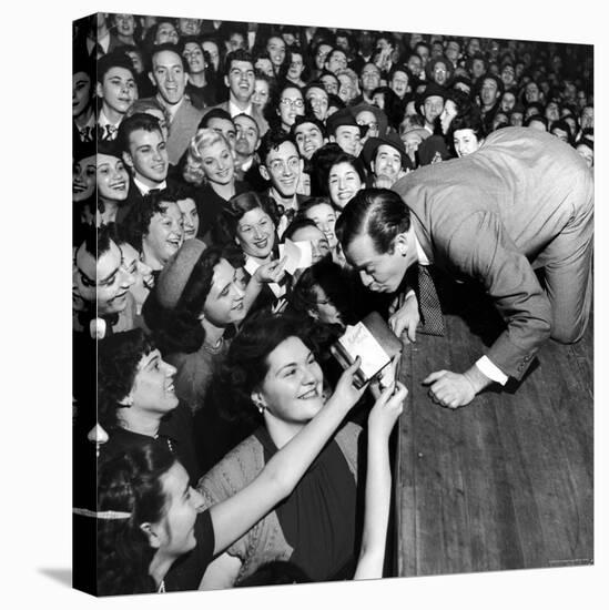 Comedian Milton Berle Trying to Kiss Fans Who Are Asking for Autographs-George Silk-Stretched Canvas