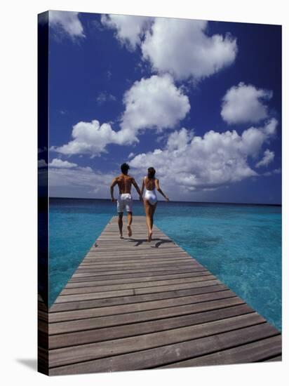 Couple Running on Dock, Curacao, Caribbean-Greg Johnston-Stretched Canvas