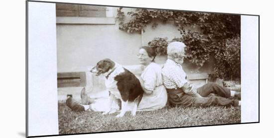 Couple Sitting Back to Back in a Garden, with Dog-null-Mounted Photographic Print